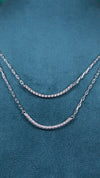 Silver chain necklace on a teal fabric background