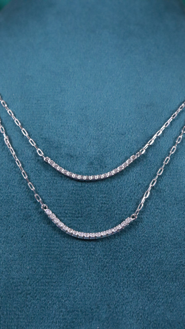 Silver chain necklace on a teal fabric background